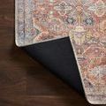 Corner of rug flipped over exposing black non-slip backing and edge stitching detail