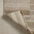 Folded corner reveals underside backing texture and sewn edges of offset-striped fringe rug