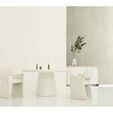 Dining table placed centrally with two white chairs, candles, and greenery in a glass vase on textured wall background