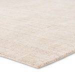 Close-up angled view showing textured pile and edge binding of cream striped rug
