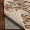 Corner of rug lifted to reveal non-slip rug pad underneath on hardwood floor