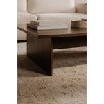 Side view of Everett Coffee Table styled with books and decor, positioned on a beige textured rug.