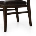 Detailed view of dark oak wood legs and connecting wooden supports under leather seat cushion