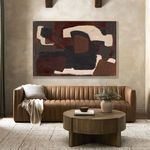 Abstract painting above tan sofa with textured throw and round wooden table in cozy living room