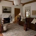 Milena rug styled in a living room with brown sofa, armchair, wooden side table, and window with beige roman shade.