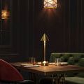 Traipse lamp ambient setting on wooden table with green tufted velvet bench and red chair nearby