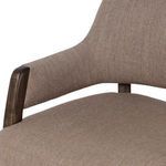 Detailed view of wood armrest and brown fabric upholstery near the seat edge