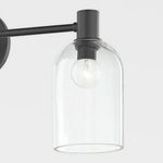 Side view focusing on one clear glass bell shade and black metal fixture arm
