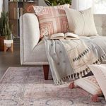 Living room arrangement showing more of the rug's pattern with sofa cushions and tassel details in soft colors