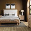 Full bedroom scene with matching dressers, lamps, area rug, and art above bed in brown room