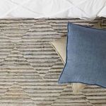 Overhead shot of blue pillow resting over beige pillow on patterned textured rug