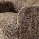 Close-up focusing on rounded armrest covered in soft taupe shearling upholstery