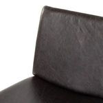 Close-up of rear leg and frame corner with charcoal black leather seat on dining chair