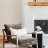 Part of living room showing the rug under a green velvet armchair and small black side table