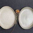 Comparison of two Mame Dessert Plates, one beige and one gray-green, with dry flowers on a black background