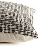 Side view of pillow showing thickness and contrast between woven front and smooth cream back fabric