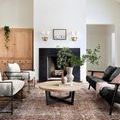 Jules Terracotta rug styled in modern living room with white walls, black fireplace, and wood coffee table
