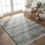 Blue and gray striped rug styled in bright room with wood floor and modern armchairs near window