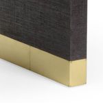Close-up of black raffia texture and smooth antique brass foot with rivet details
