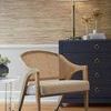Edward Lounge Chair in room setting with navy blue rug, dark dresser, and gold table lamp