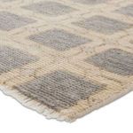 Close-up showing hand knotted texture and fringed edge of gray and ivory geometric patterned rug