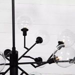 Close-up of multiple clear glass bulbs and matte black rods from angled perspective