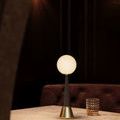 Lamp illuminated on marble tabletop with textured amber glass and dark chair framing