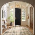 Rug laid in a bright entryway under natural light with black door and wood floor