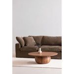 Styled with dark brown sofa and cream rug against a plain white wall, showing side profile of the table