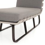 Side close-up showing charcoal cushion resting on curved wooden slats with dark metal legs