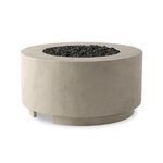 Round outdoor fire table in natural concrete with a wide top and center filled with black lava stones