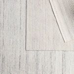 Layered rug image focusing on backside woven texture with folded edges in neutral tones