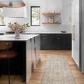 Long runner version of the rug placed in a modern kitchen with black and white cabinetry and wood floor
