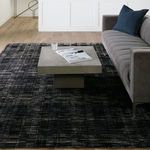 Side view of sofa and coffee table on rug showing wood floor and white paneled wall