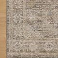 Partial top view of rug corner on light wood floor showing detailed pattern and edge binding