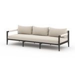 Angled side view of Sherwood sofa emphasizing clean aluminum frame and sand-colored fabric
