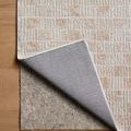 Back corner of Townes Beige Clay Rug folded to show non-slip rug pad underneath