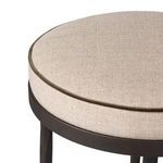 Close-up of round cushioned seat with fabric upholstery and dark piping detail