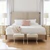 King beige upholstered bed in bright room with natural daylight and sheer curtains, featuring blush throw and accent pillow