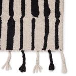 Zoomed detail of braided knotted fringes alternating black and ivory at rug edge