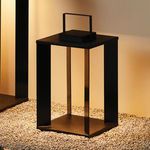 Hanley Solar LED Lantern styled outdoors on gravel with wall casting warm ambient light
