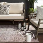 Side view of rug under beige sofa and chair with candles inside black lanterns and a white watering can in foreground