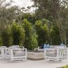 Four Newport Swivel Club chairs arranged around fire pit on patio with trees and blue pillows