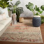 Rug styled in light-filled indoor space with white sofa, plants, and decorative pouf