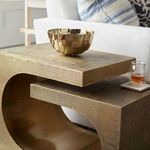 Close-up of smaller Dali Side Table with decorative shiny brass bowl and glass on coaster styled next to sofa