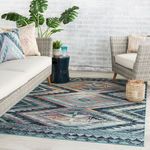 Indoor setting featuring rug under rattan furniture and cushions with tribal designs
