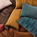 Multiple pillows in various colors and textures with the blue diamond lattice pillow on top