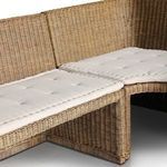 Close-up angle of cushioned corner joint with beige fabric tufting over rattan base