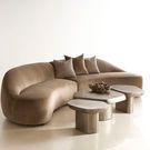 Living room scene with three interlocked Clawson tables in graphite finish in front of a tan curved sofa