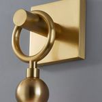 Close-up of aged brass finish showing circular ring and mounting plate against gray background